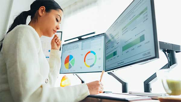 Mujer revisa gráficos de rendimiento en pantalla usando IA para optimizar campañas de marketing digital.
