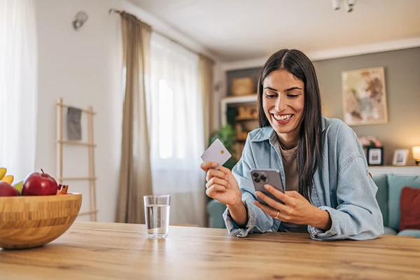 Consumidora realiza una compra digital con su teléfono y tarjeta