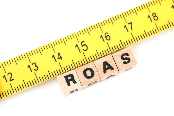 Cinta métrica junto a letras ROAS para evaluar la rentabilidad